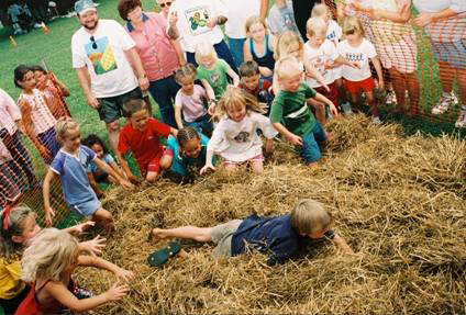 A group of people in hay bales with a boy laying on the ground.