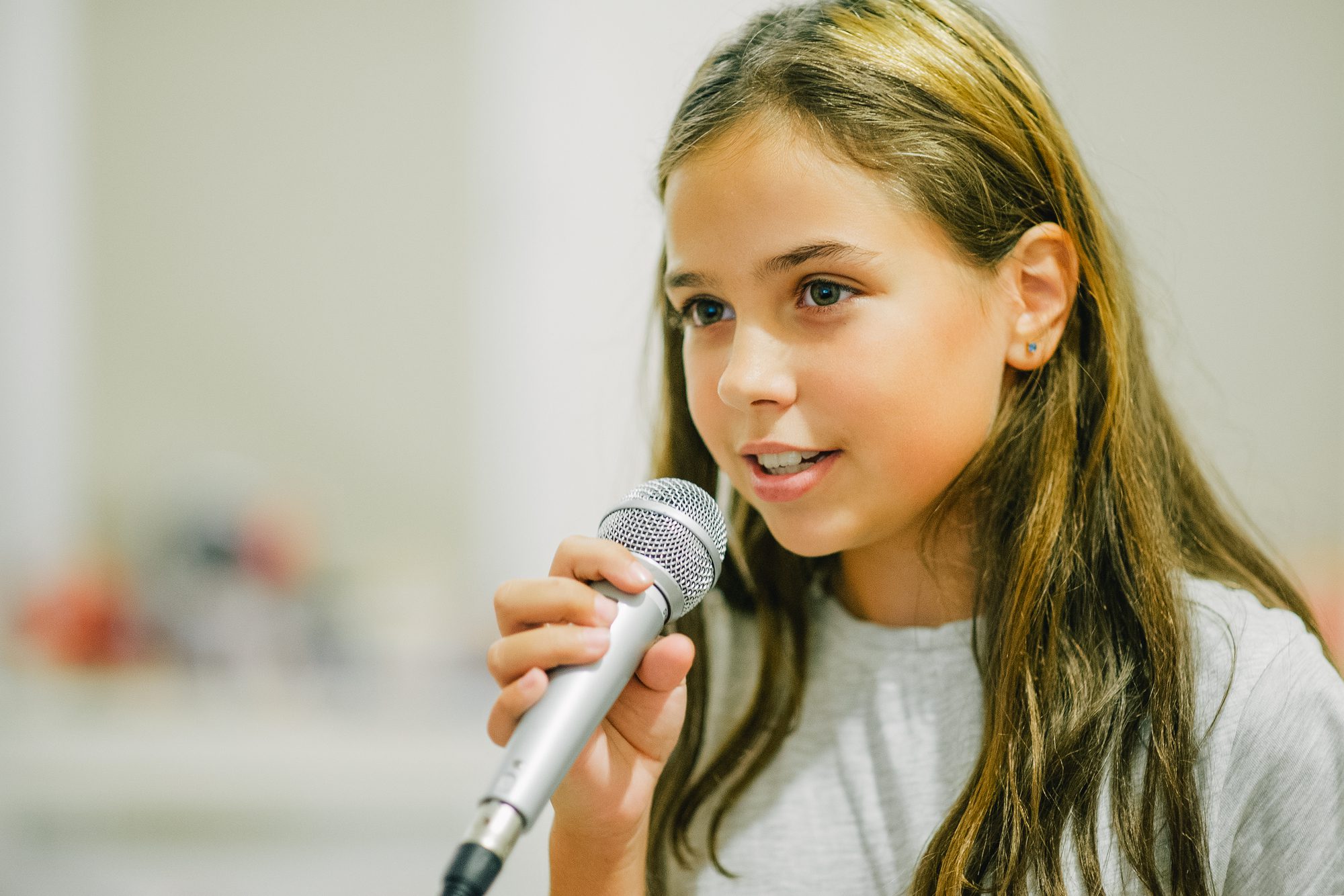 A girl holding a microphone up to her mouth.