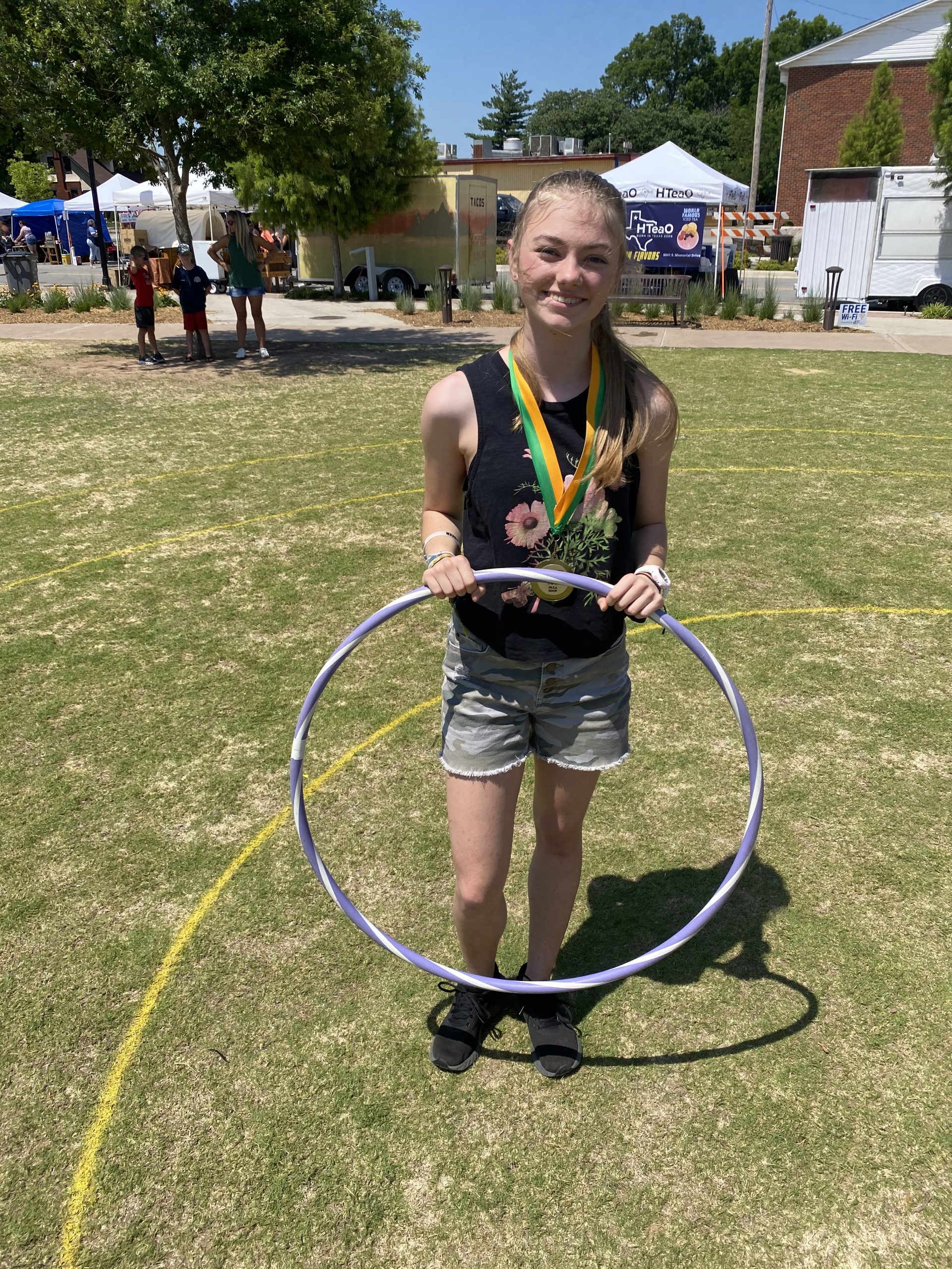 A girl holding a hula hoop in the grass.